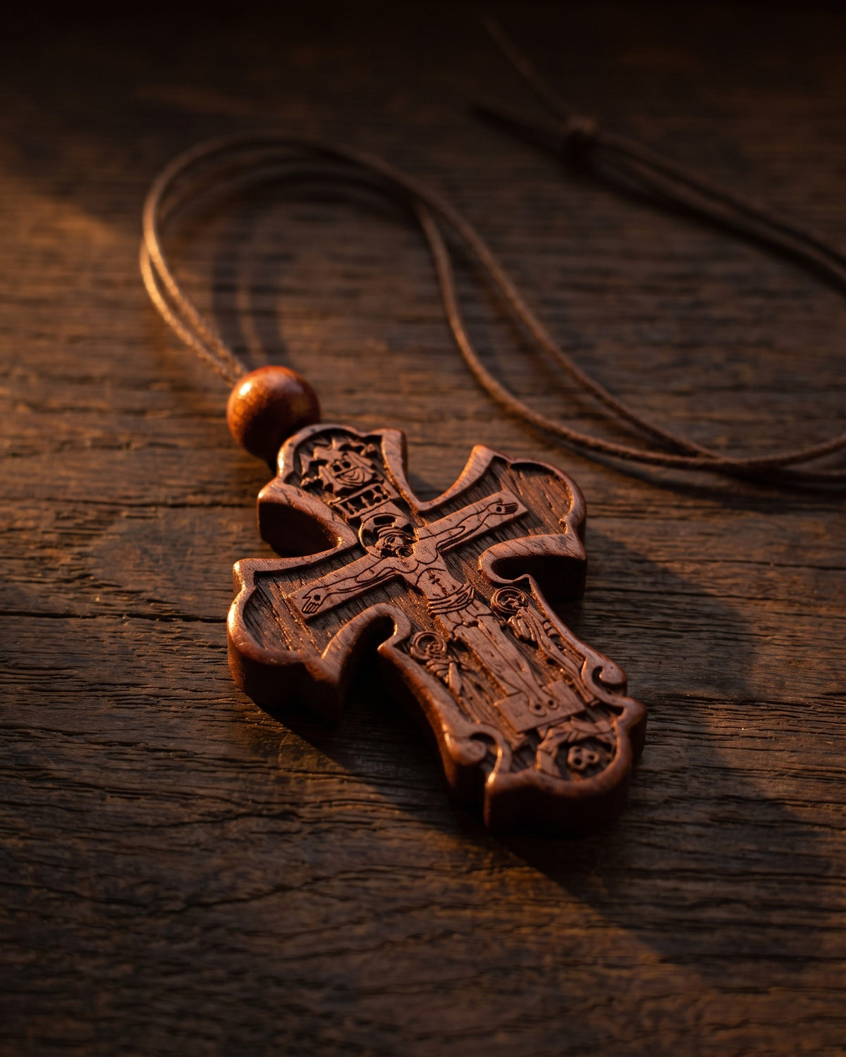 The carved cross pendant on dark oak in warm light