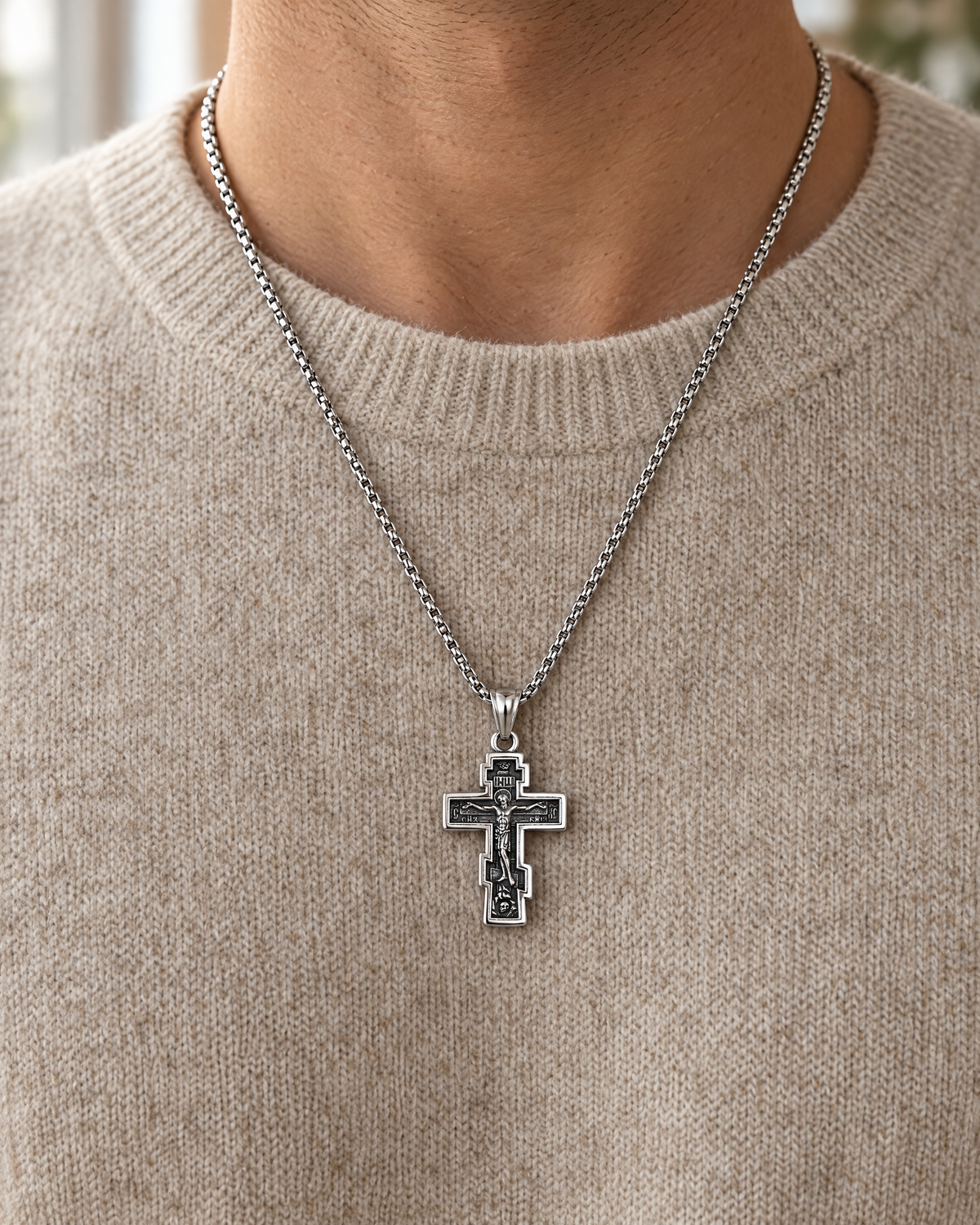 Silver Orthodox cross necklace worn over a knit sweater