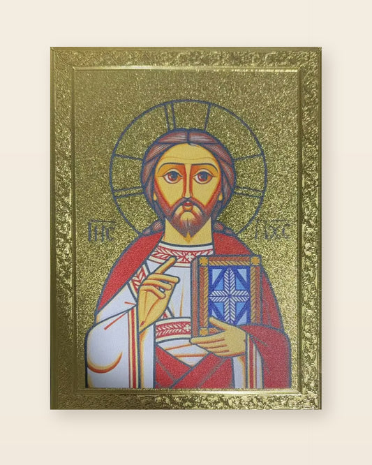 Gold relief icon of Christ Pantocrator in an ornate embossed frame, right hand raised in blessing, left hand holding the Gospel